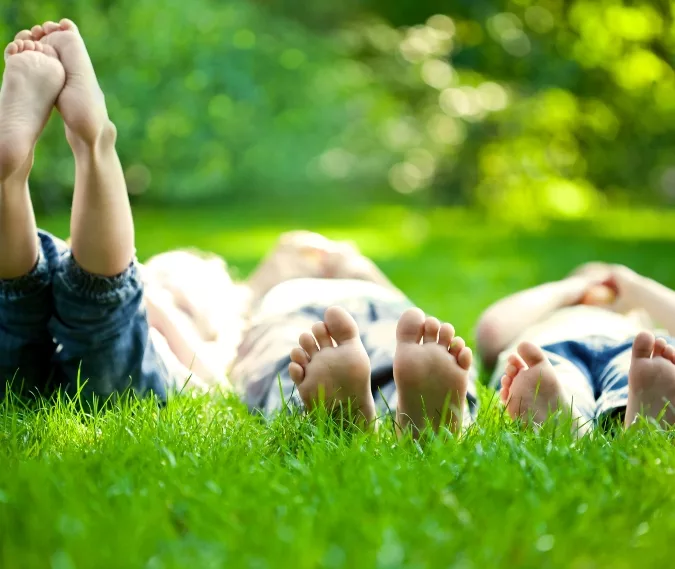 three children laying barefoot in the grass